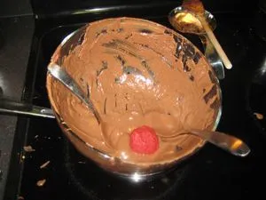 Dipping the red velvet ball into the chocolate cream cheese frosting (opens in a new tab)