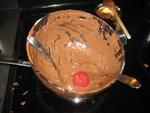 Dipping the red velvet ball into the chocolate cream cheese frosting